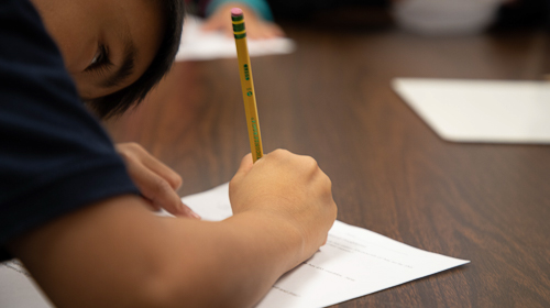 Student writing at his desk in a classroom 